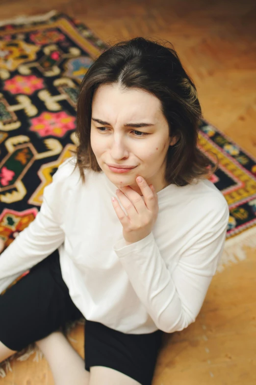 a young woman sitting on the floor in front of a rug