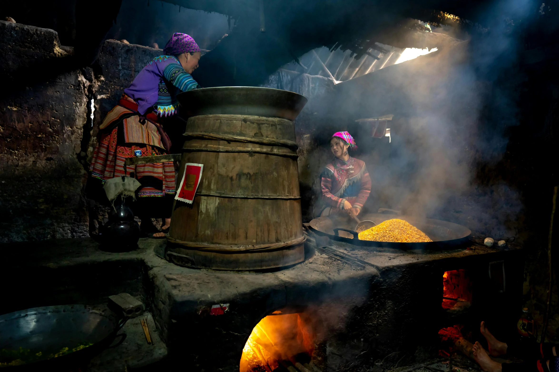 two women prepare food inside of a clay oven