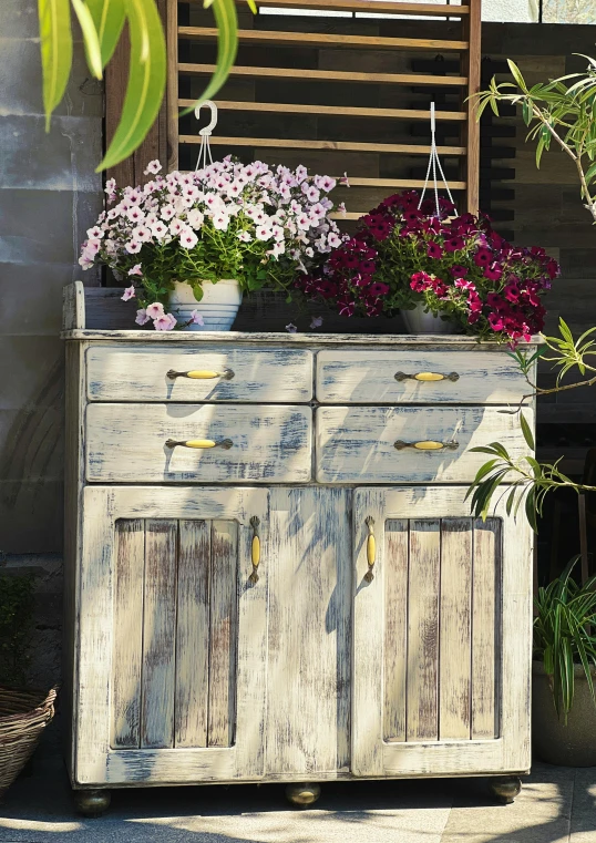 flowers in wooden pot on old white cabinet