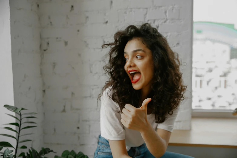 a woman with an excited look holding her hand up and sitting on a couch