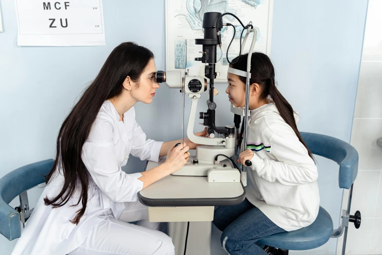 two women look into a microscope at their own eyes