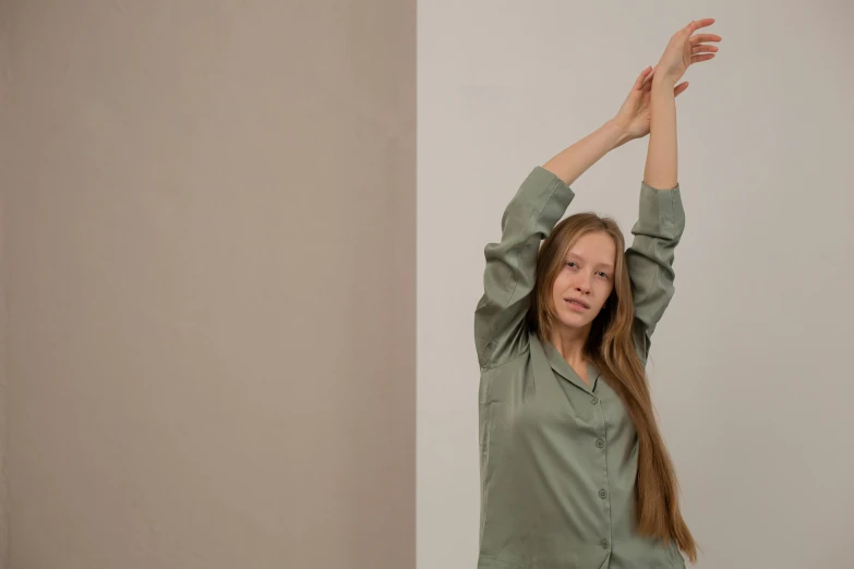 a woman in green shirt holding her hands above her head