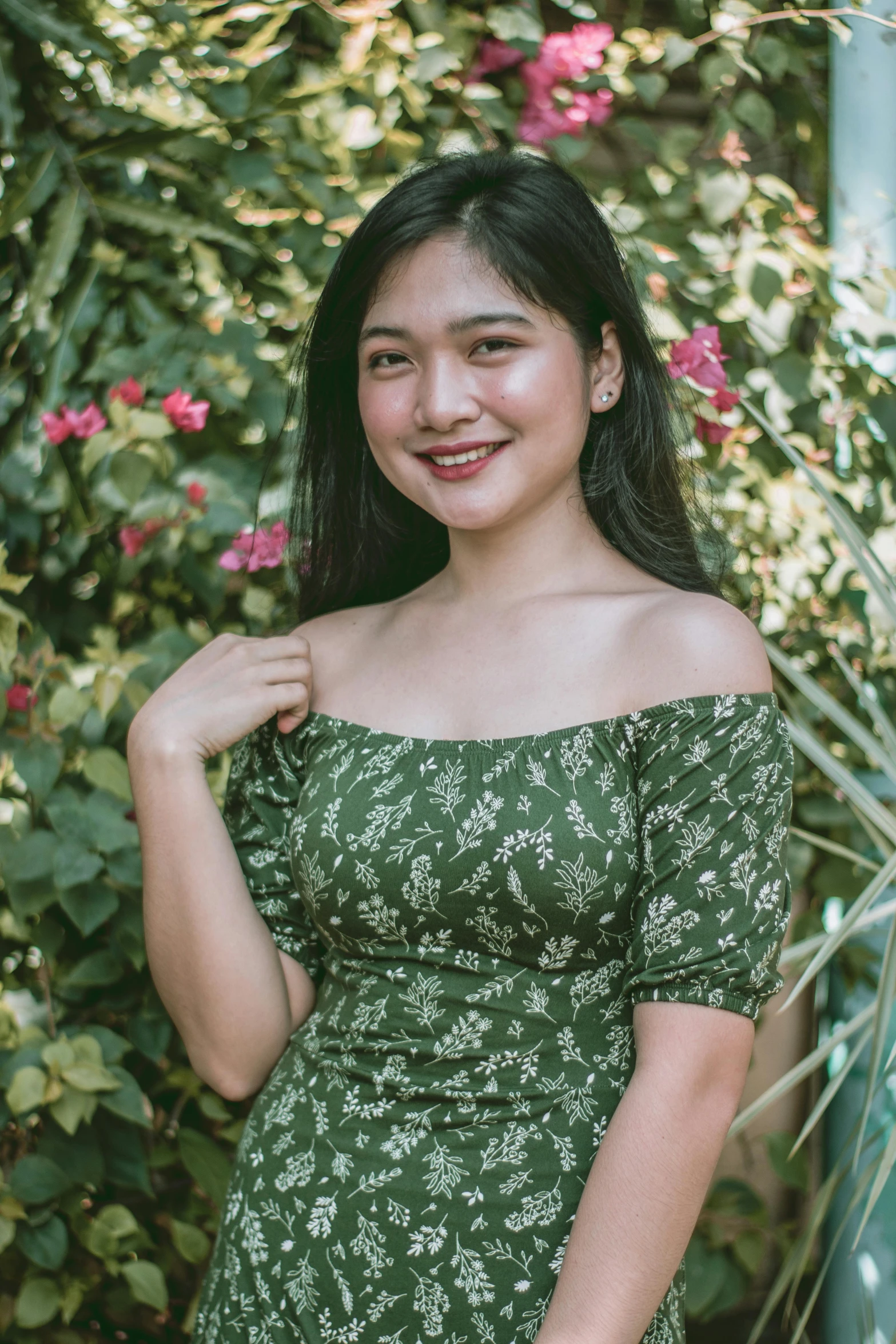 a woman posing for a picture in front of a bush