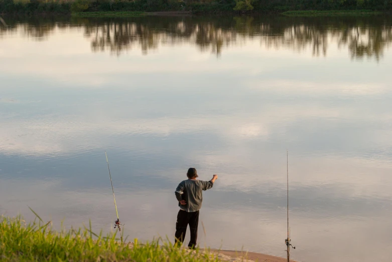 a man is standing by a pond while fishing