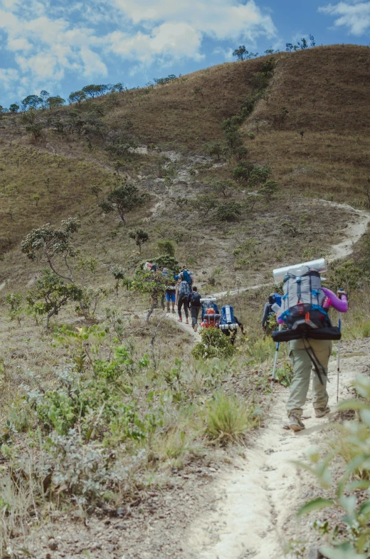 a line of people hiking up a dirt path