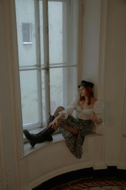 two beautiful women in hats and long skirts sitting by a window