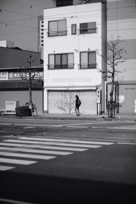 black and white image of a person on skateboard next to an apartment building