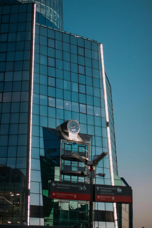 a clock stands against the glass exterior of a building