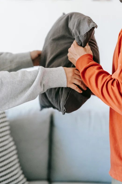 two adults in orange sweaters pulling stuffed animal out