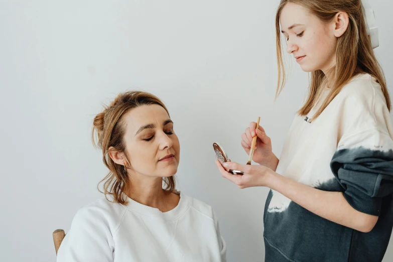 a woman and a little girl are both taking the temperature of her cell phone