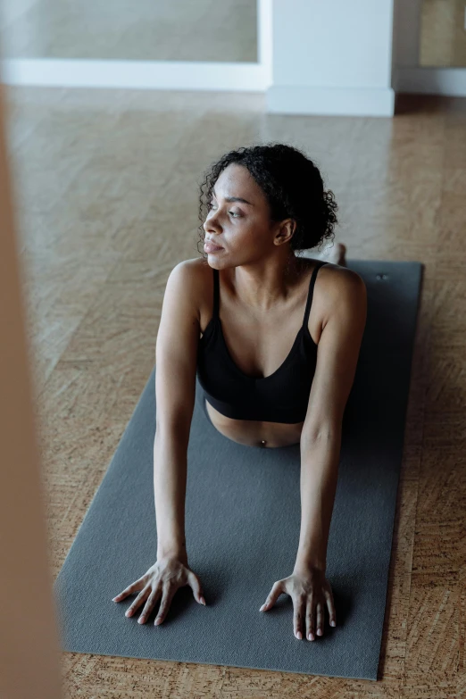 a woman wearing a black  poses on a yoga mat