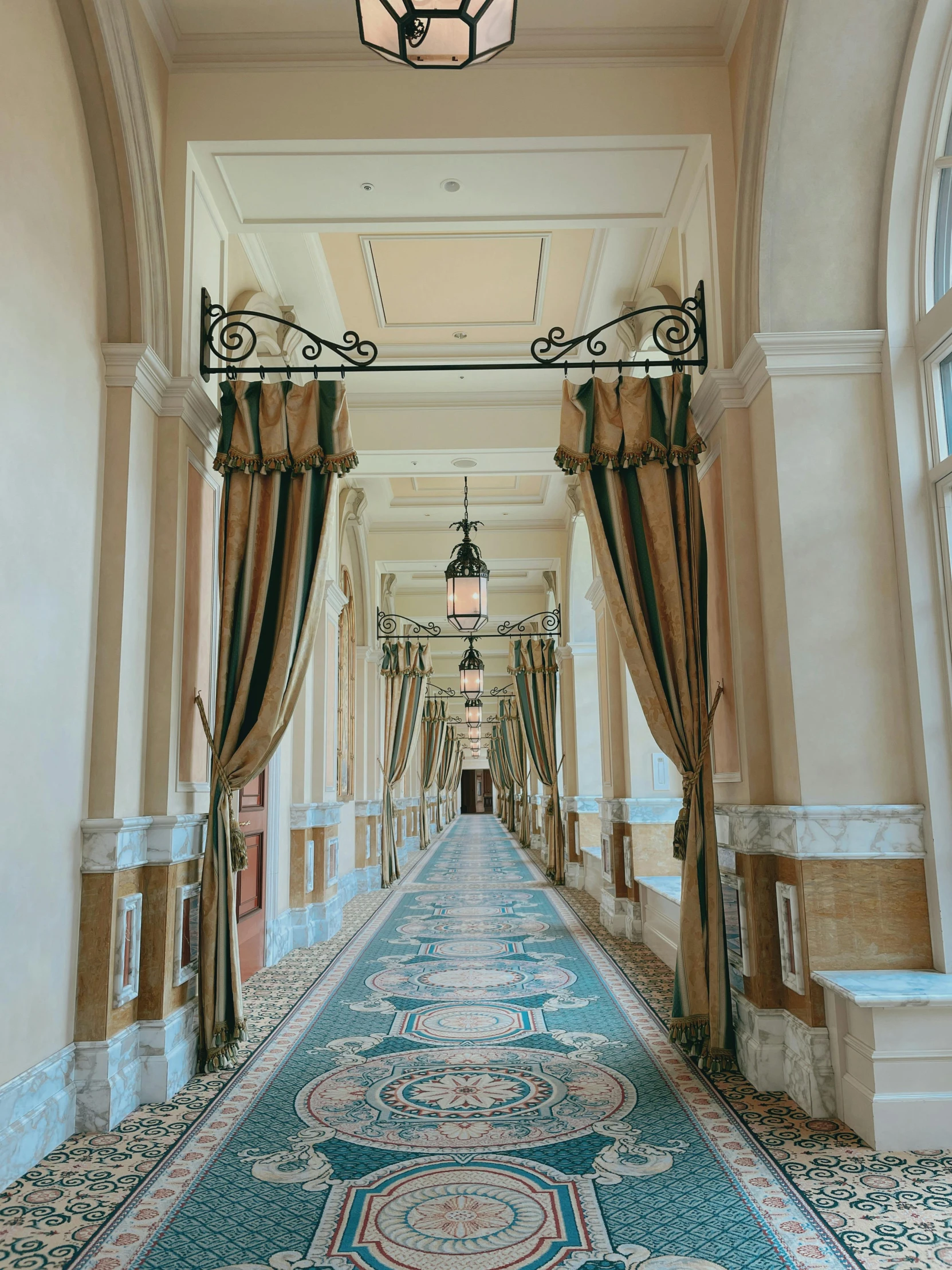 a room with many pillars, blue and pink curtains, and a floor rug