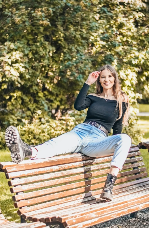 a beautiful young woman sitting on a wooden park bench