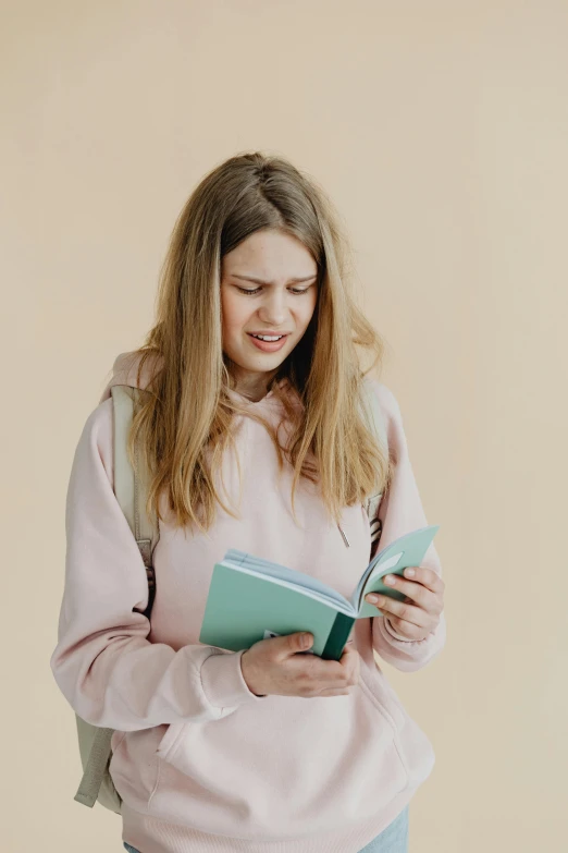 a pretty young lady standing while holding a book