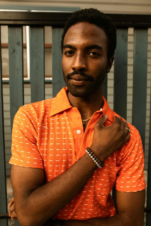 a man with tattoos wearing an orange shirt