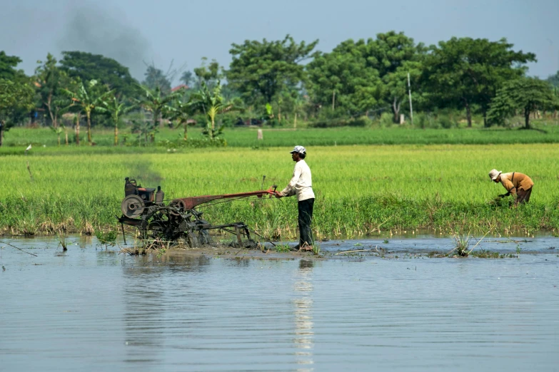 two people working in the mud near the water