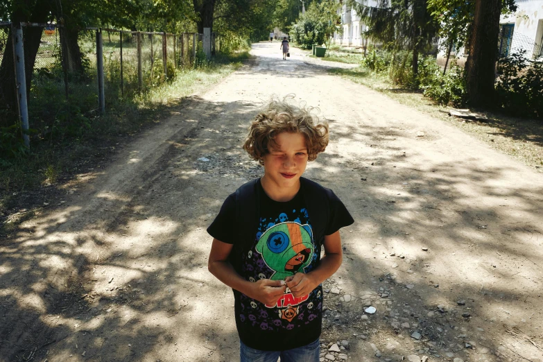 there is a boy that is standing in the dirt with a disc