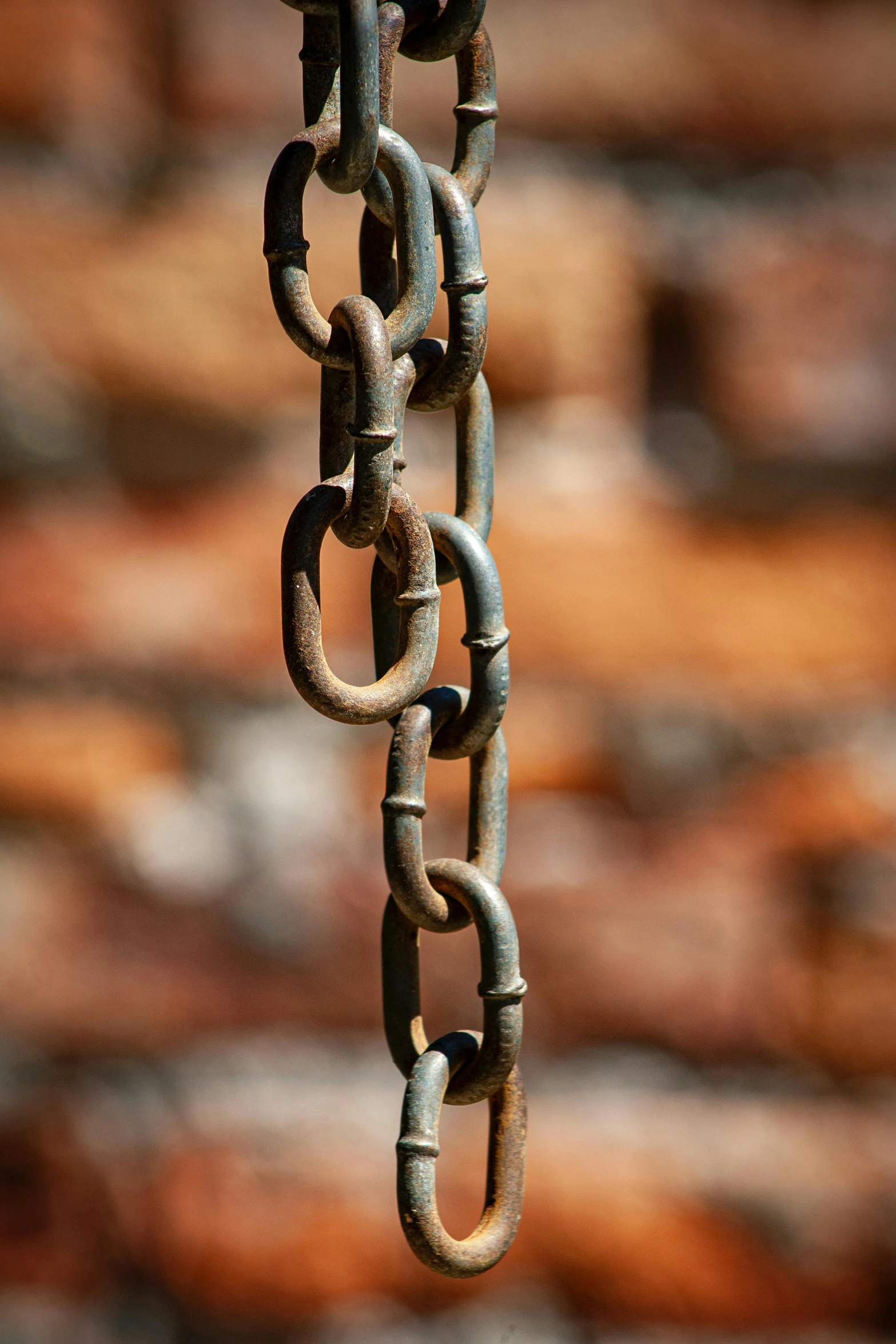 closeup of old rusty chain links on a brick wall