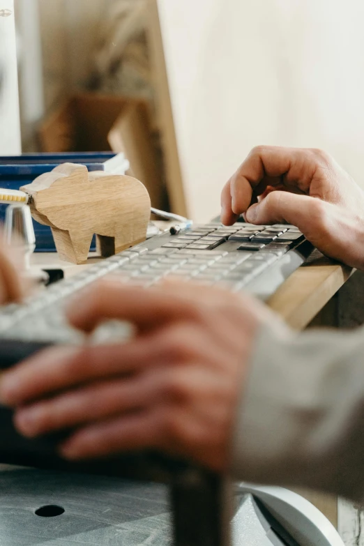 two hands typing on a keyboard, while a person is working on another