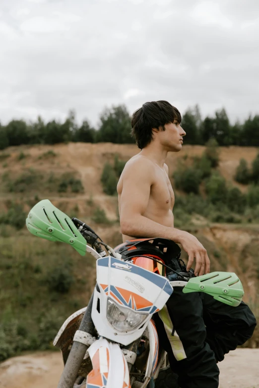 a man with  standing next to his motorcycle