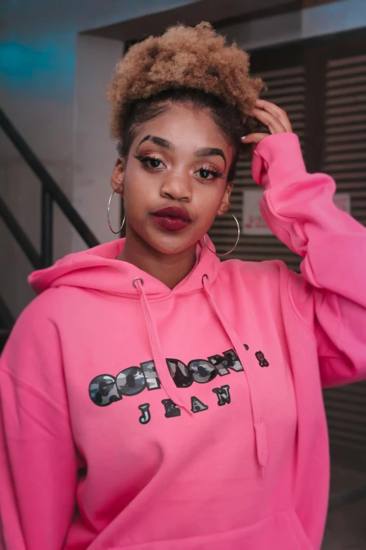 a woman wearing a pink sweatshirt standing in front of stairs