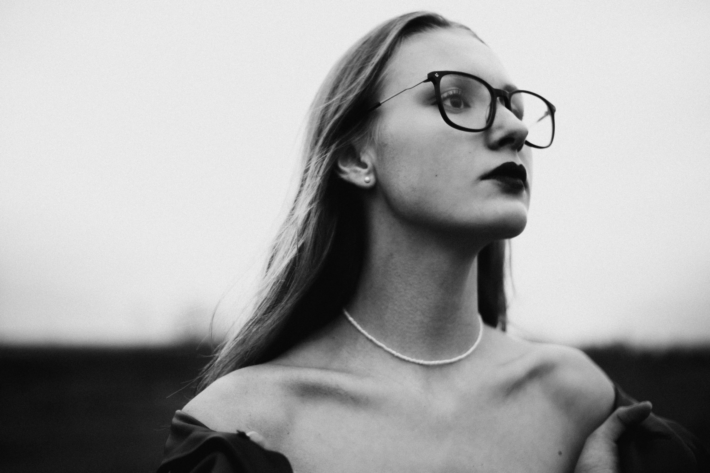 a woman wearing glasses, is looking up and she has long hair