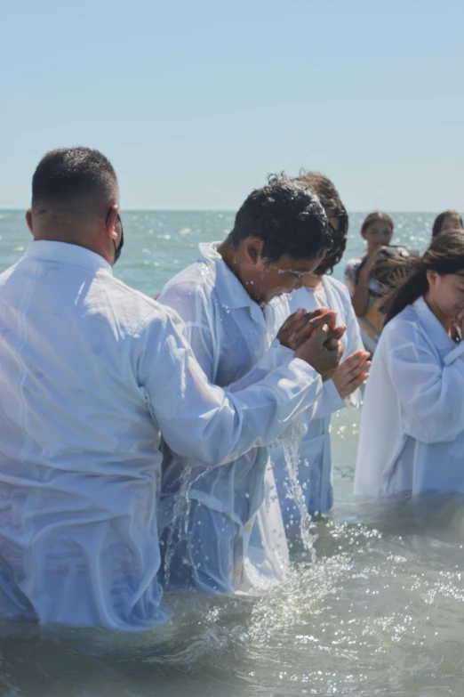 several people that are wearing white suits in the water