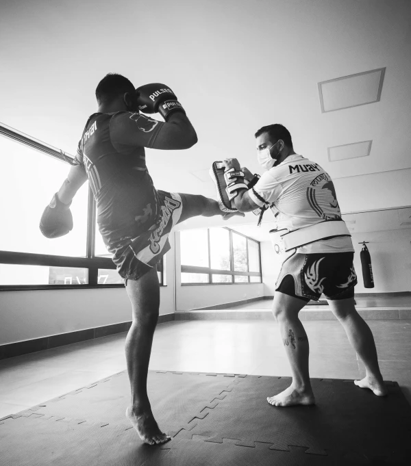 two young men practicing kickbox in an open building