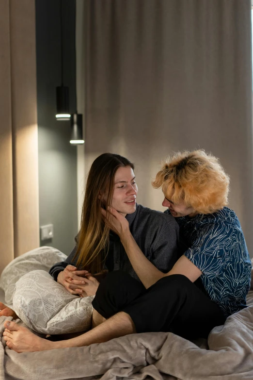 a lady and a blonde haired woman are sitting on a bed