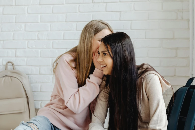 two girls sitting next to each other on a couch