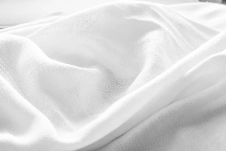 the top portion of a white bed with white sheeting