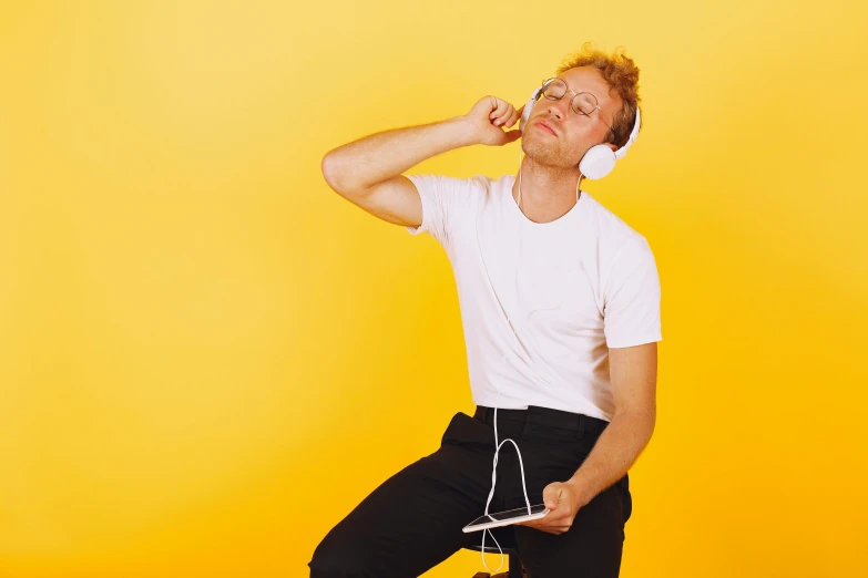 the man in white shirt is listening to headphones