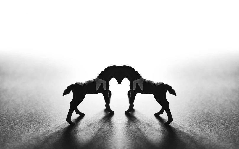 two toy horses that are standing next to each other