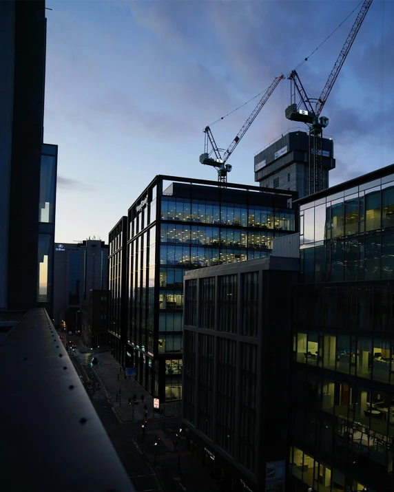 a building being built at dusk with cranes in the background