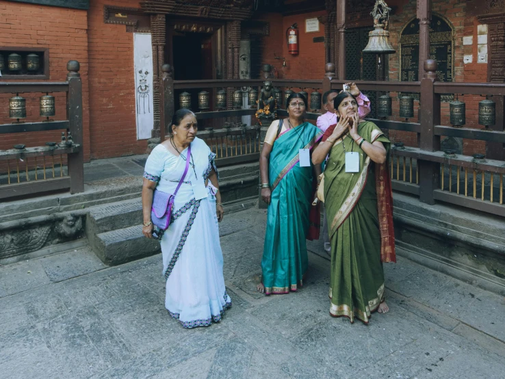 a group of three women standing outside of a building