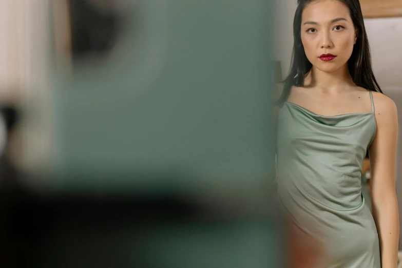 an asian woman wearing a green dress is looking straight ahead