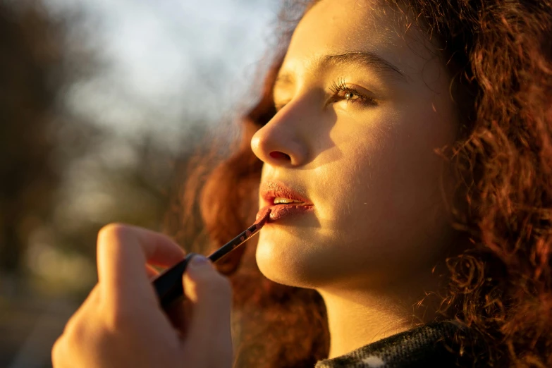 young woman with red hair brushes her lip