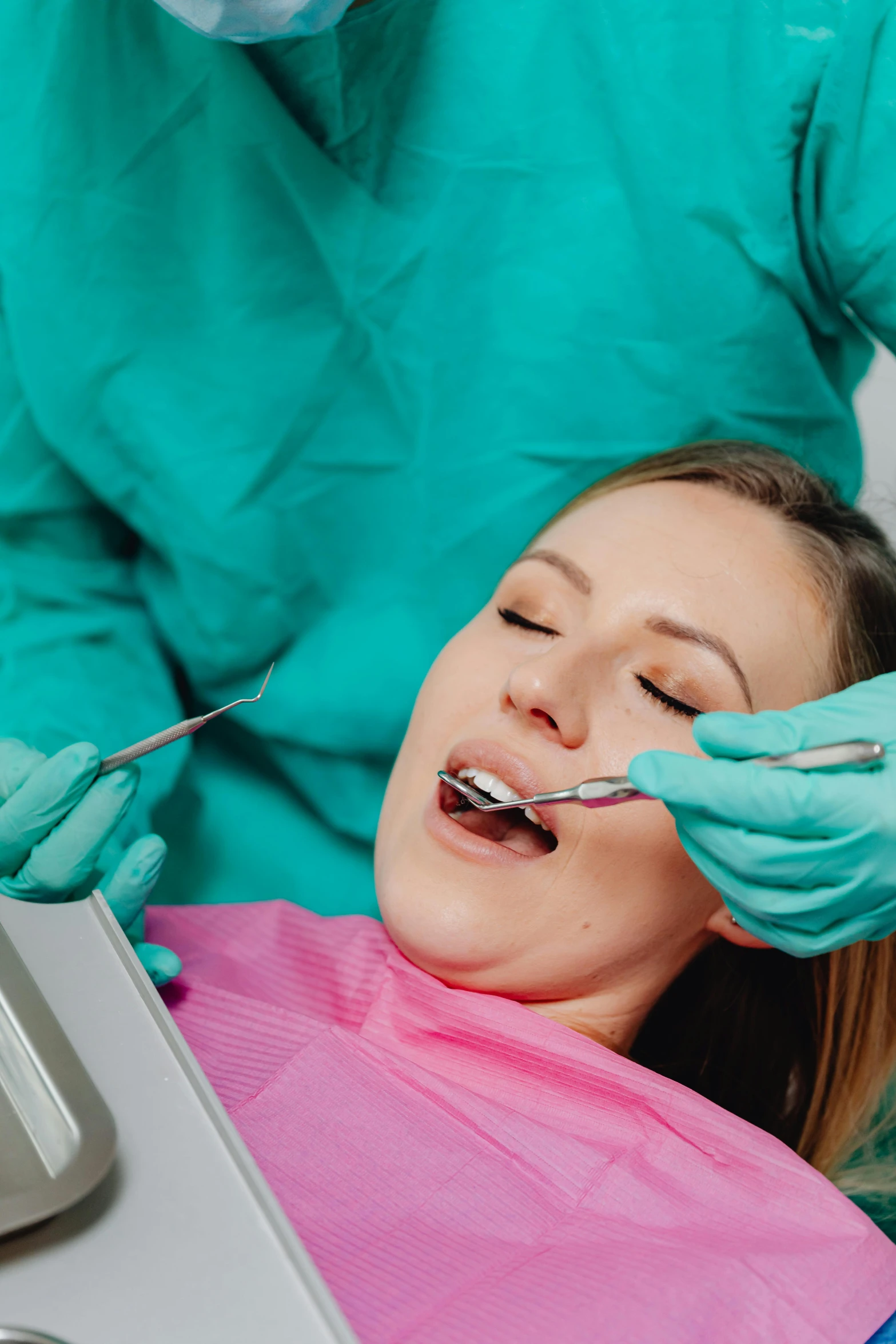 a female doctor performing dental checks on the woman's teeth