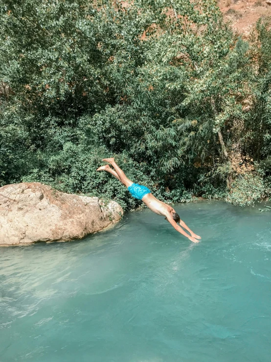 a man floating in a stream by some big rocks