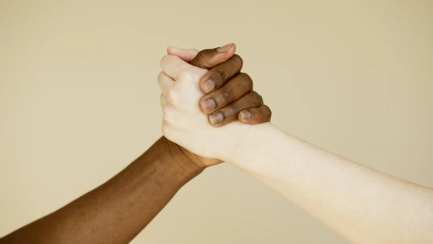 two people holding hands in front of a beige background