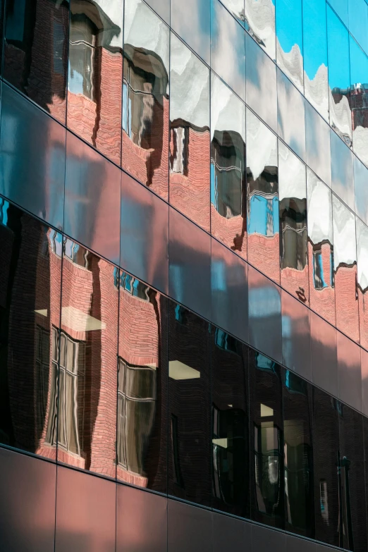 a large brick building has a large mirror reflection of the surrounding windows