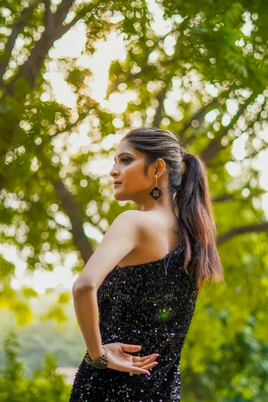 young woman standing in front of tree looking out