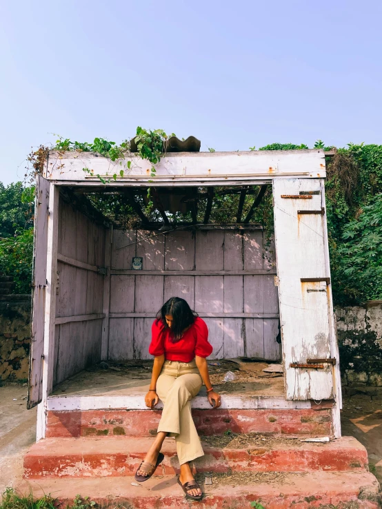 a woman sitting outside of an old out door