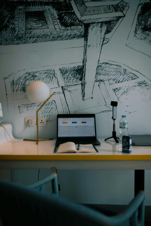 a computer desk with a drawing on the wall behind it