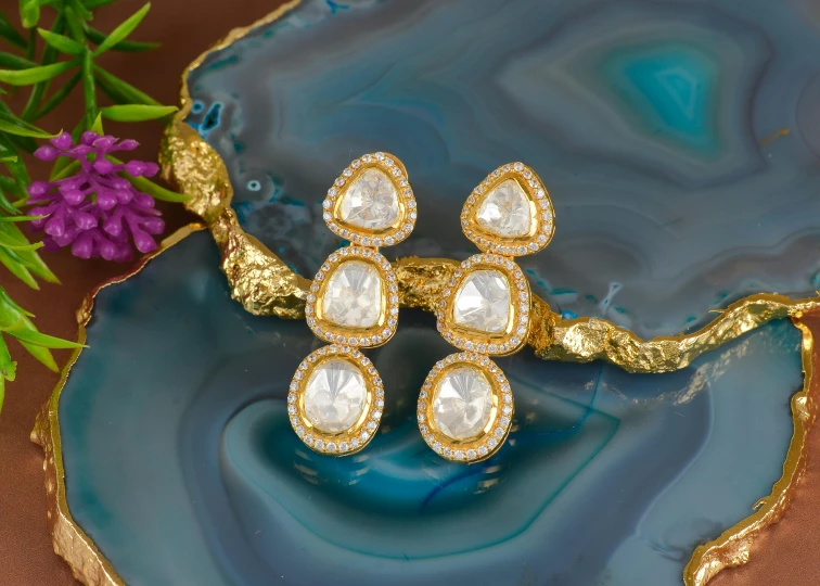 a blue plate topped with two pairs of gold earrings