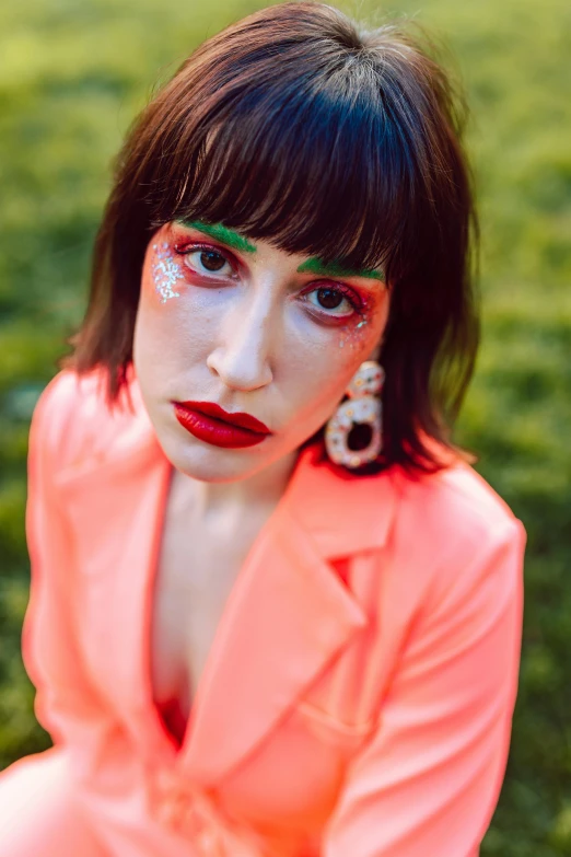 woman in pink outfit with green makeup and dark hair