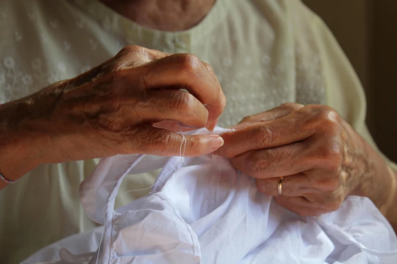 two hands on the front of an older womans white shirt