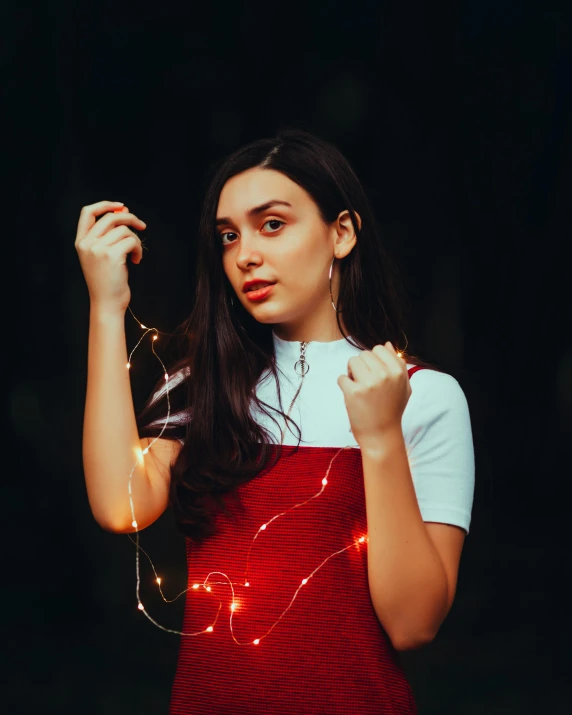 a woman wearing an apron holds a string of christmas lights