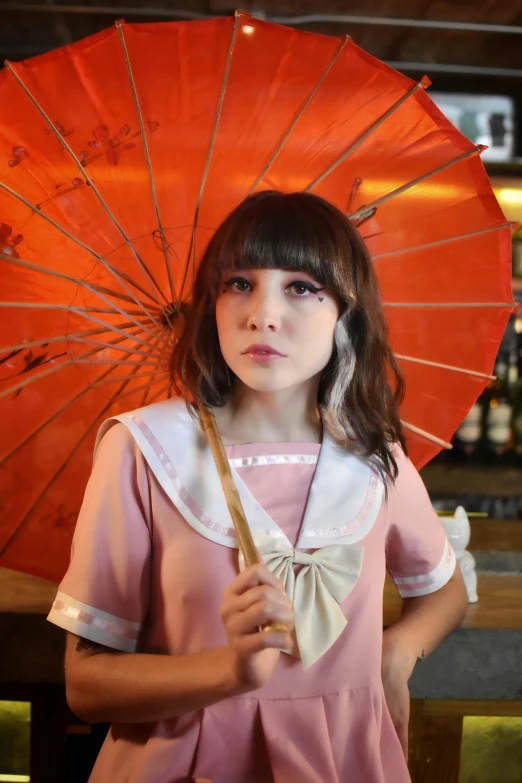 a little girl in pink and white dress holding an orange umbrella