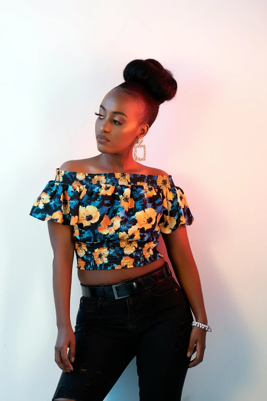 a woman with a flowery top standing next to a white wall